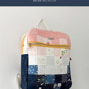 May include: A patchwork Phoenix backpack with a pink, white, and navy blue design. The bag features a yellow zipper and white straps. The bag size is 14"h x 12"w x 4"d. The text "COTTON AND JOY PATTERNS" and "PHOENIX BACKPACK" are visible.