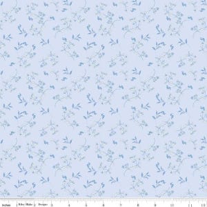 May include: A light blue fabric with a repeating floral pattern. Delicate white and blue flowers and leaves are scattered across the surface. The fabric has a soft, pastel color palette, creating a gentle and airy feel. The design is by Riley Blake Designs.
