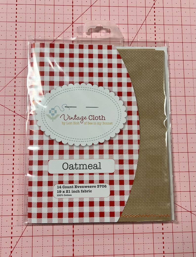 May include: A package of 14 count oatmeal colored evenweave fabric for cross stitch. The fabric is 19 by 21 inches and is 100% cotton. The package has a red and white gingham pattern.