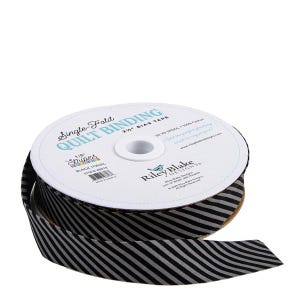 May include: A spool of black and gray striped single-fold quilt binding tape. The label reads "Single-Fold Quilt Binding" and "2 1/2" Bias Tape". The tape is 1/8" wide and made of 100% cotton.