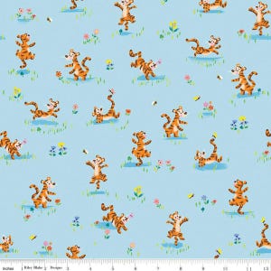 May include: A light blue fabric with a repeating pattern of orange and black cartoon tigers in various poses. The tigers are surrounded by small yellow flowers, green leaves, and butterflies.