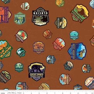 May include: A brown fabric with a repeating pattern of colorful national park patches. The patches feature names like "Yosemite", "Zion", "Glacier", "Grand Canyon", "Rocky Mountain", "Great Smoky Mountains", "Bryce Canyon", "Petrified Forest", "Redwood", "Volcanoes", "Biscayne", "Shenandoah", "Denali", "Badlands", "North Cascades", "Kenai Fjords", "American Samoa", "Roosevelt", "Katmai", "Guadalupe", "Mount Rainier", "Death Valley", "Indicate", "Bryce Canyon", "Las Vegas Volcanoes", "Capitol Reef", "and "Dry Tortugas".