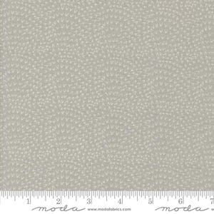 May include: A light gray fabric with a repeating pattern of small, white arrow-like shapes. The fabric has a textured appearance and a ruler is visible along the bottom edge. The fabric is suitable for quilting and other sewing projects.