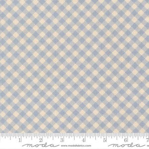 May include: A fabric swatch featuring a light blue and cream gingham check pattern. A white ruler is visible at the bottom edge, showing measurements in inches from 0 to 7. The text moda and www.modafabrics.com are printed on the white border.