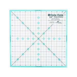 May include: A turquoise 11-inch ruler with a grid pattern and small flower shapes. The ruler is labeled "Cute Cuts - 11" Trim-it Ruler" by Lori Holt of Bee in my Bonnet.