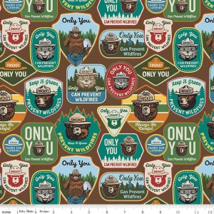 May include: Brown fabric featuring Smokey Bear patches in various shapes. The patches include Smokey Bear illustrations, the text "Only You Can Prevent Wildfires," and the phrase "Keep It Green." The design incorporates teal, red, and yellow accents.