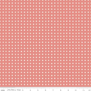 May include: A coral-colored fabric with a repeating pattern of small, off-white squares arranged in a grid. The fabric is measured in inches along the bottom edge, with the Riley Blake Designs logo visible.