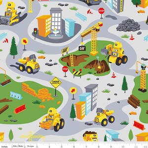 May include: A colorful fabric featuring a repeating pattern of construction vehicles, buildings, and road signs. The vehicles are yellow and black with the word "CAT" on them. The buildings are gray and white. The road signs are red and white and say "STOP".