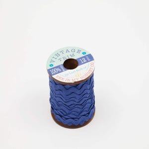 May include: A spool of vintage blue trim with a wavy edge. The spool has a label that reads "VINTAGE TRIM" and "BEE IN MY BONNET CO." The trim is 12 inches in length and is made of 100% cotton.