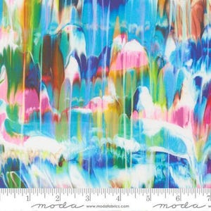 May include: A fabric swatch featuring a vibrant, multi-colored abstract pattern with vertical drips of blue, pink, green, yellow, and white. A white ruler with black markings and the text "moda" is visible along the bottom edge of the fabric.