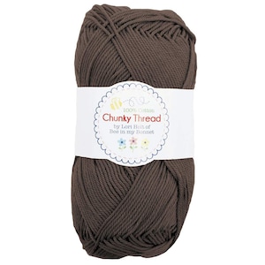 May include: A ball of brown chunky cotton thread with a white label. The label reads "100% Cotton Chunky Thread" with the text "by Lori Holt of Bee in my Bonnet". The thread is tightly wound and ready for crafting.