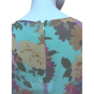 May include: A sleeveless dress with a floral pattern. The dress features a light blue background with large flowers in shades of yellow, brown, and pink. A zipper runs down the back of the dress.