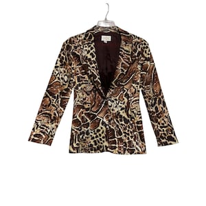 May include: A brown and tan animal print blazer with long sleeves. The blazer has a notched collar and a single-button closure. The interior lining is a dark brown color. The blazer is hanging on a clear hanger.