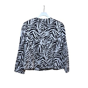 Puede incluir: Chaqueta con estampado de cebra en blanco y negro con mangas largas. La chaqueta est&aacute; colgada de una percha blanca sobre un fondo blanco. El patr&oacute;n es un dise&ntilde;o audaz y repetitivo.