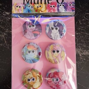 May include: Set of 7 colorful round buttons featuring cartoon images of My Little Pony characters with googly eyes. The buttons are pink, blue, yellow, purple, and green.