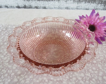 Pode incluir: Uma tigela de vidro rosa com uma borda festonada. A tigela tem um design canelado e é feita de vidro transparente com um tom rosado.