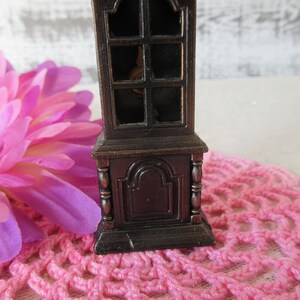 Puede incluir: Un sacapuntas de estilo vintage con forma de reloj de abuelo de madera. El sacapuntas est&aacute; hecho de metal y tiene un acabado marr&oacute;n oscuro. Tiene una ventana de vidrio en la parte delantera y un peque&ntilde;o caj&oacute;n en la parte inferior.