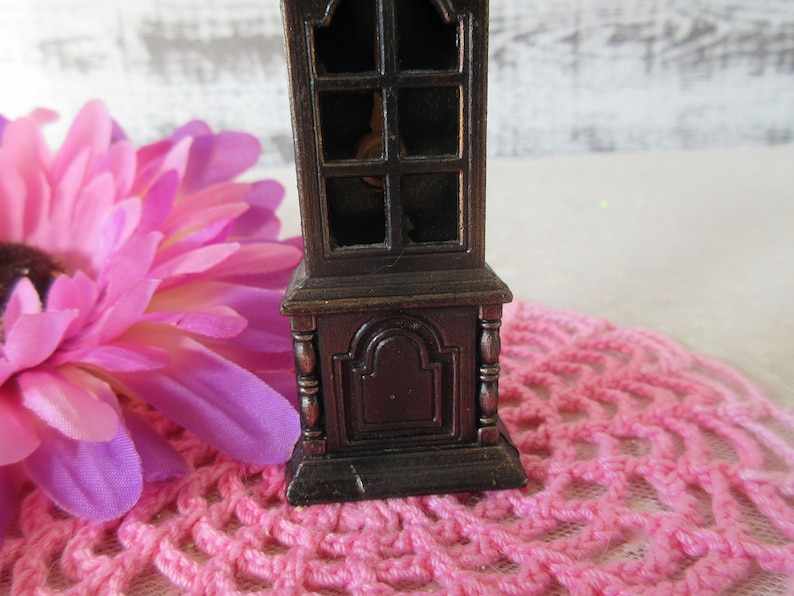 Puede incluir: Un sacapuntas de estilo vintage con forma de reloj de abuelo de madera. El sacapuntas est&aacute; hecho de metal y tiene un acabado marr&oacute;n oscuro. Tiene una ventana de vidrio en la parte delantera y un peque&ntilde;o caj&oacute;n en la parte inferior.