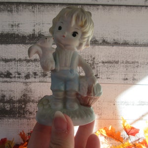 Figurine de petit garçon avec un écureuil et un panier portant