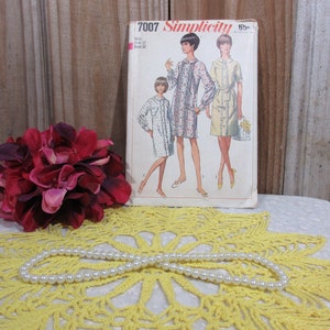 May include: Vintage Simplicity sewing pattern number 7007 for a dress. The pattern is for sizes 12-18 and is priced at 65 cents. The pattern shows three women wearing different versions of the dress.