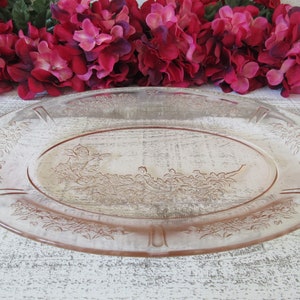 May include: A vintage oval glass serving platter with a delicate floral design in a pale pink colour. The platter has a raised rim and a smooth surface.