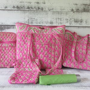 Puede incluir: Una colección de bolsos de tela acolchada con un patrón de cachemira rosa brillante con detalles en verde y blanco, que incluye una mochila, un bolso grande, un bolso más pequeño, un estuche y un paraguas cilíndrico verde lima.