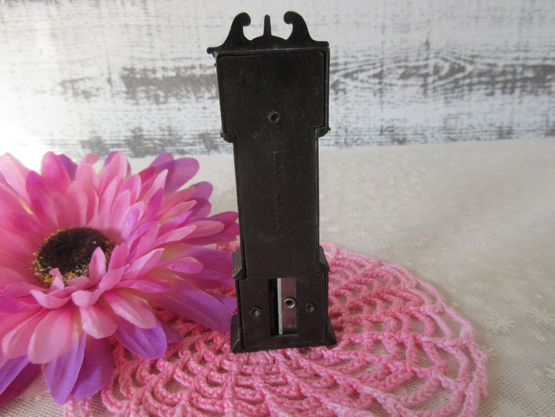Puede incluir: Sacapuntas de pl&aacute;stico negro con forma de reloj de pie. El sacapuntas tiene una ranura para l&aacute;pices y un peque&ntilde;o caj&oacute;n para recoger las virutas.