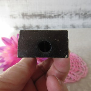 Puede incluir: Un sacapuntas de madera negro con un agujero redondo en el centro.
