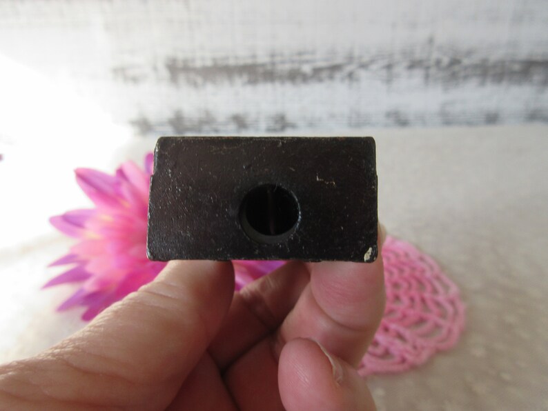 Puede incluir: Un sacapuntas de madera negro con un agujero redondo en el centro.