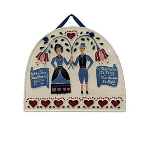 May include: A semi-circular ceramic wall plaque featuring a couple in blue and black attire. Text on the left reads "When Two Fond Hearts Unite" and on the right "The Yoke Is Easy The Burden Is Light." Decorated with red hearts and floral motifs.