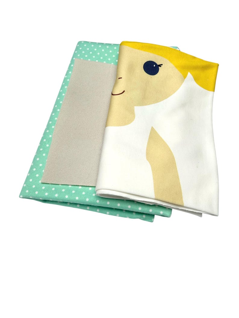 May include: A set of three fabric squares for crafting. The top square features a cartoon girl with blonde hair and a blue eye. The middle square is a solid beige color. The bottom square is a light green fabric with white polka dots.