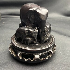 Seven carved elephants on a ebony base.