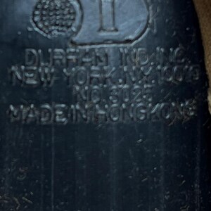 May include: Close-up of a black plastic object with the text "WALT DISNEY PRODUCTIONS" and "DURAN IND. INC. NEW YORK, N.Y. 10023 NO. 8025 MADE IN HONGKONG".
