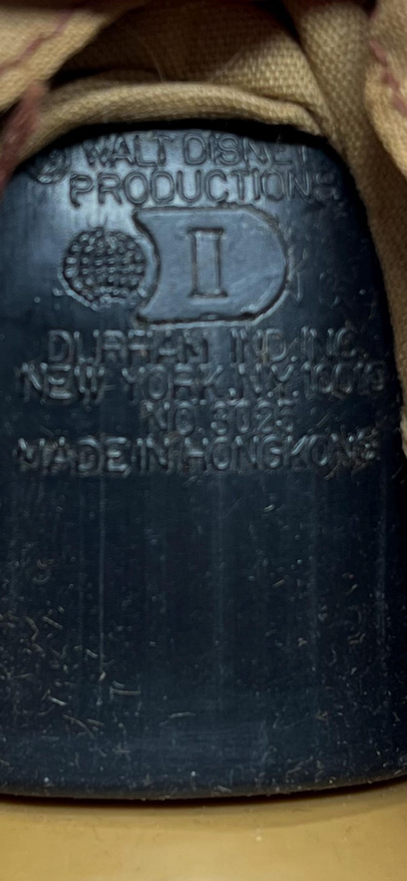 May include: Close-up of a black plastic object with the text "WALT DISNEY PRODUCTIONS" and "DURAN IND. INC. NEW YORK, N.Y. 10023 NO. 8025 MADE IN HONGKONG".