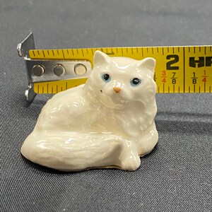 Miniature porcelain cat figurine.