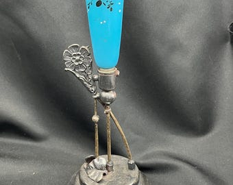 May include: A vintage bud vase with a turquoise glass body and a silver-toned metal base. The vase features hand-painted floral designs in pink, white, and black. The metal base has an ornate, Art Nouveau-inspired design.