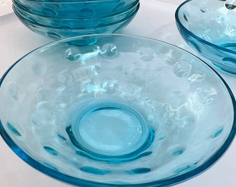 May include: A set of six turquoise blue glass bowls with a textured, bubbled surface. The bowls are stacked on top of each other, with the largest bowl at the bottom and the smallest bowl at the top.