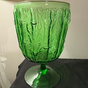 Op de afbeelding: Een groene glazen vaas met een getextureerd bamboe ontwerp. De vaas heeft een brede basis en een lang, slank lichaam.