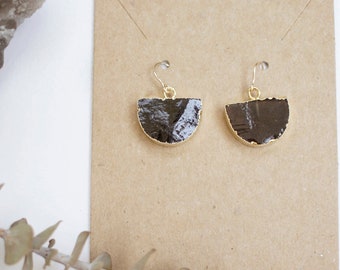 May include: A pair of gold earrings with black and white semi-circular stone accents.