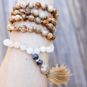 Pode incluir: Um bracelete de contas brancas e marrons com um tassel. O bracelete &eacute; feito de pedras naturais e tem um design simples.