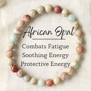May include: A bracelet made of African Opal beads in a variety of colors, including beige, brown, red, and blue. The bracelet is in a small white drawstring bag with the text "African Opal", "Combats Fatigue", "Soothing Energy", and "Protective Energy" printed on it.
