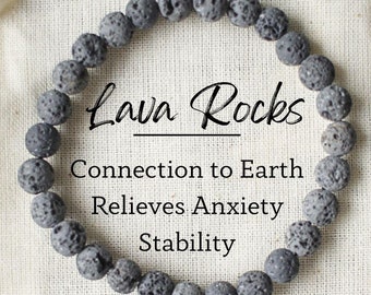 Puede incluir: Un brazalete de piedra de lava negra en una bolsa de cordón blanco. La bolsa tiene el texto "Lava Rocks" y "Connection to Earth, Relieves Anxiety, Stability".