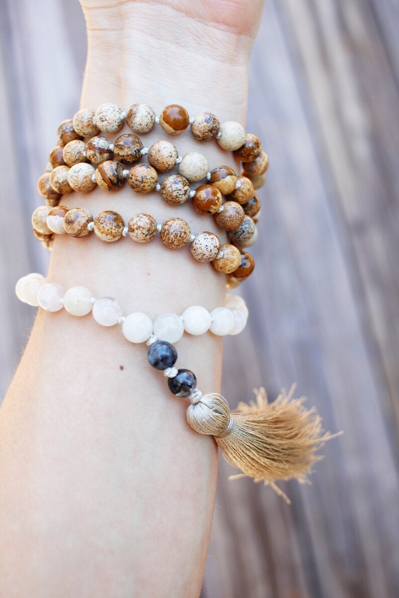 Pode incluir: Um bracelete de contas brancas e marrons com um tassel. O bracelete &eacute; feito de pedras naturais e tem um design simples.