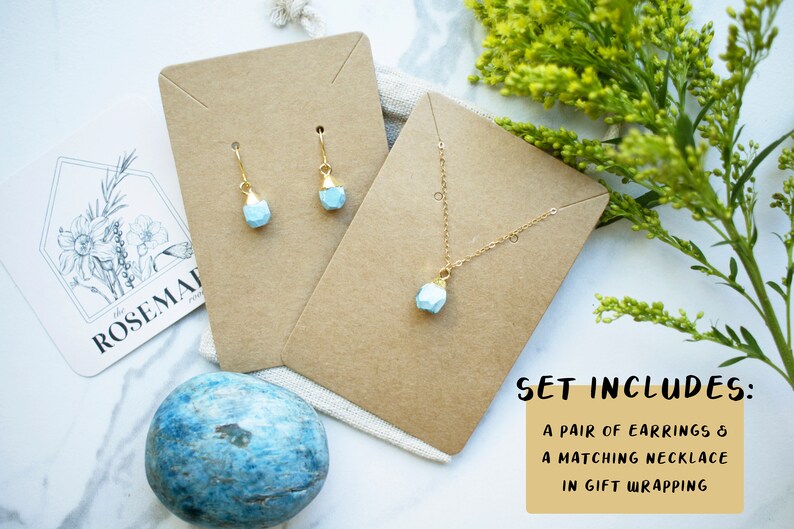 Puede incluir: Un conjunto de joyas de piedra preciosa azul claro sobre cartulina marr&oacute;n. El conjunto incluye un par de pendientes y un collar a juego. El texto "SET INCLUDES: A PAIR OF EARRINGS & A MATCHING NECKLACE IN GIFT WRAPPING" est&aacute; impreso sobre un fondo amarillo.