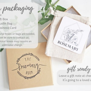 Pode incluir: Uma caixa de presente marrom com um r&oacute;tulo branco que diz "The Rosemary Room". A caixa est&aacute; cheia de uma bolsa de musselina branca que cont&eacute;m um cart&atilde;o com uma ilustra&ccedil;&atilde;o em preto e branco de alecrim e o texto "Rosemary".