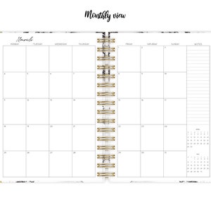 May include: A monthly planner with a marble cover and gold accents. The planner has a spiral binding and includes a calendar view for March. The planner also includes a notes section and a smaller calendar view for the year.