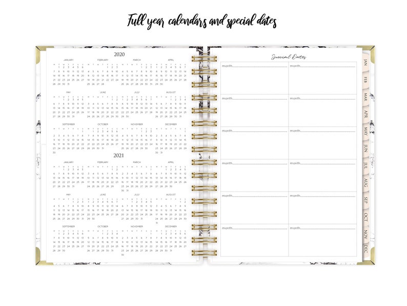 May include: A white planner with a marble design and gold accents. The planner includes full year calendars for 2020 and 2021, as well as a section for special dates. The planner has a gold coil binding.