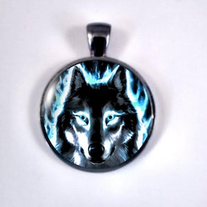 May include: A round pendant with a silver-colored bail. The pendant features a black wolf with glowing blue eyes and a blue flame-like design around the wolf's head. The pendant is likely made of metal and glass.