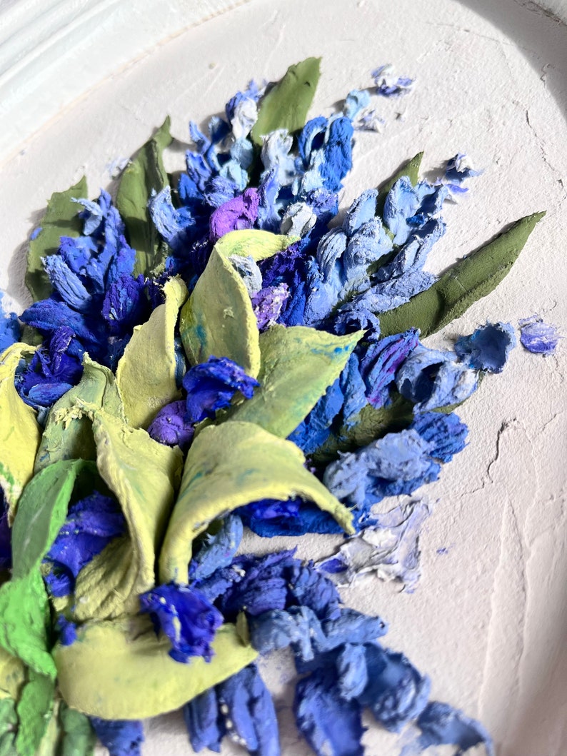 May include: A close-up of a 3D painting of blue and green flowers. The flowers are painted in a realistic style and have a textured surface.
