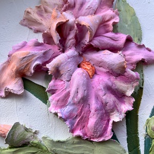 K&ouml;nnte beinhalten: Nahaufnahme einer dreidimensionalen, pinkfarbenen und orangefarbenen Iris-Bl&uuml;te mit gr&uuml;nen Bl&auml;ttern. Die Bl&uuml;te ist texturiert und scheint aus Ton zu sein.